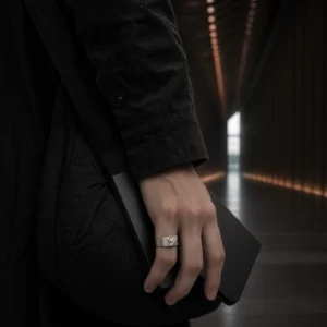 Architectural stainless steel ring on hand with geometric design in low light setting